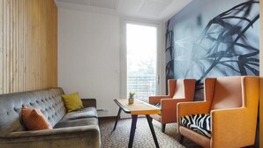 A modern living room with a grey sofa, orange armchairs, and a patterned floor. - Dyreparken Safarihotell (Kristiansand)