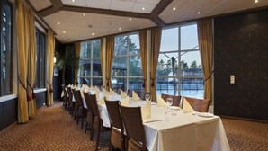 A dining area with tables set for a meal, large windows, and a view of a body of water. - Dyreparken Safarihotell (Kristiansand)