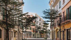 Una calle bordeada de edificios de varios pisos, con balcones y ventanas de arco.