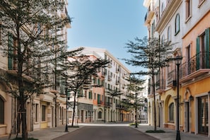 Una calle bordeada de edificios de varios pisos, con balcones y ventanas de arco.