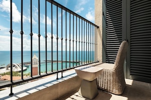 A balcony with a view of the sea, a chair, and a table.