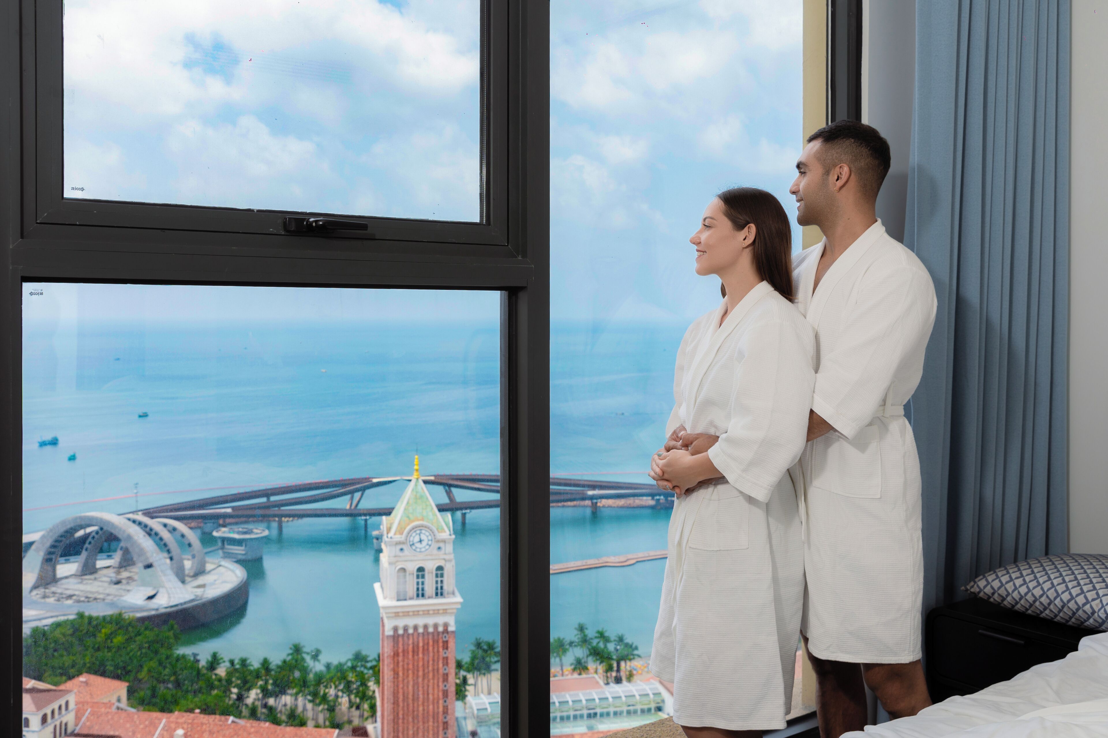 Una habitación con un ventanal grande que da a una vista panorámica de la ciudad, incluyendo un puente y una torre del reloj.