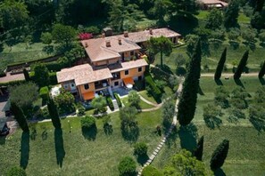 A multi-story building with a central courtyard, surrounded by lush greenery and tall trees. - Appartamenti Arca and Ca Mure (Bardolino)
