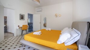 A hotel room with a bed, a chair, a desk, a mirror, and a bathroom visible through an open door. - GuestHost - Large room ideal for two, featuring a private bathroom and located in a villa in Borgo Lucia, a complex with a large shared garden. Surrounded by greenery, the accommodation is located in Selva di Fasano, a quiet hillside hamlet in the munici (Selva di Fasano)