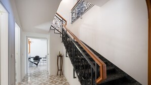A staircase with a black metal railing and wooden handrail, leading to a room with a white door and a patterned floor. - GuestHost - Large room ideal for two, featuring a private bathroom and located in a villa in Borgo Lucia, a complex with a large shared garden. Surrounded by greenery, the accommodation is located in Selva di Fasano, a quiet hillside hamlet in the munici (Selva di Fasano)