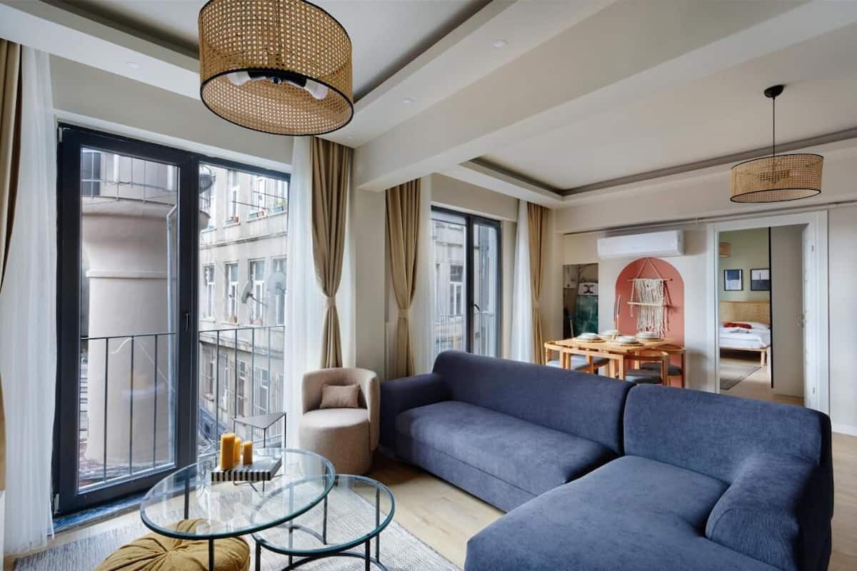 A modern living room with a large sofa, a glass coffee table, and a dining area with a table and chairs.