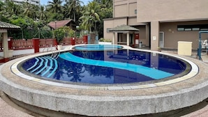 Ein runder Swimmingpool mit Steinkante, umgeben von einer niedrigen Steinmauer.