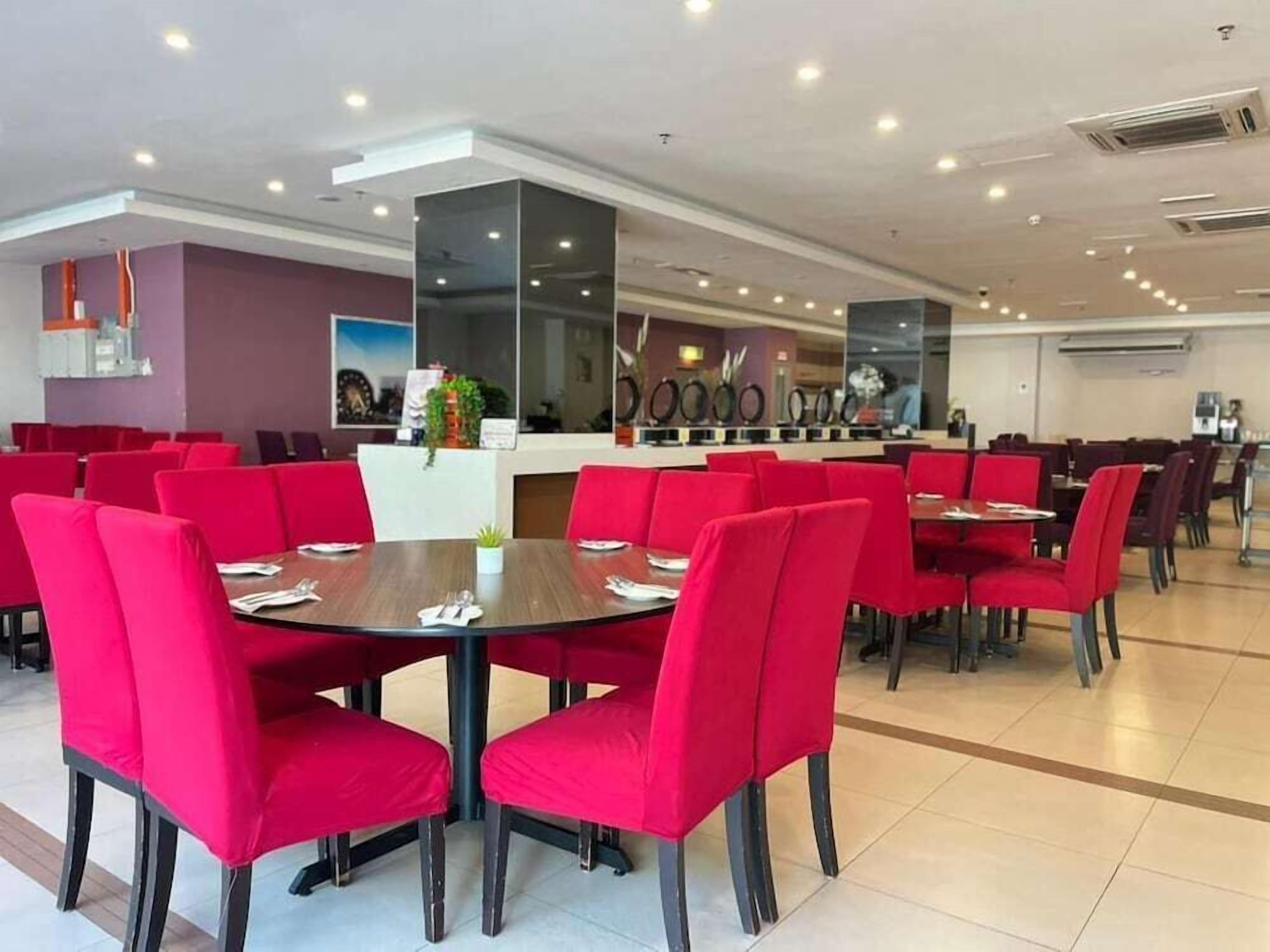 A restaurant with red chairs and tables, a counter with a menu, and a large mirror on the wall.