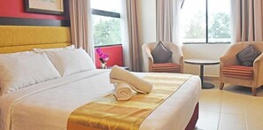A hotel room with a large bed, two armchairs, a small table, and a window with curtains. - Pantai Puteri Hotel Malacca (Malacca City)