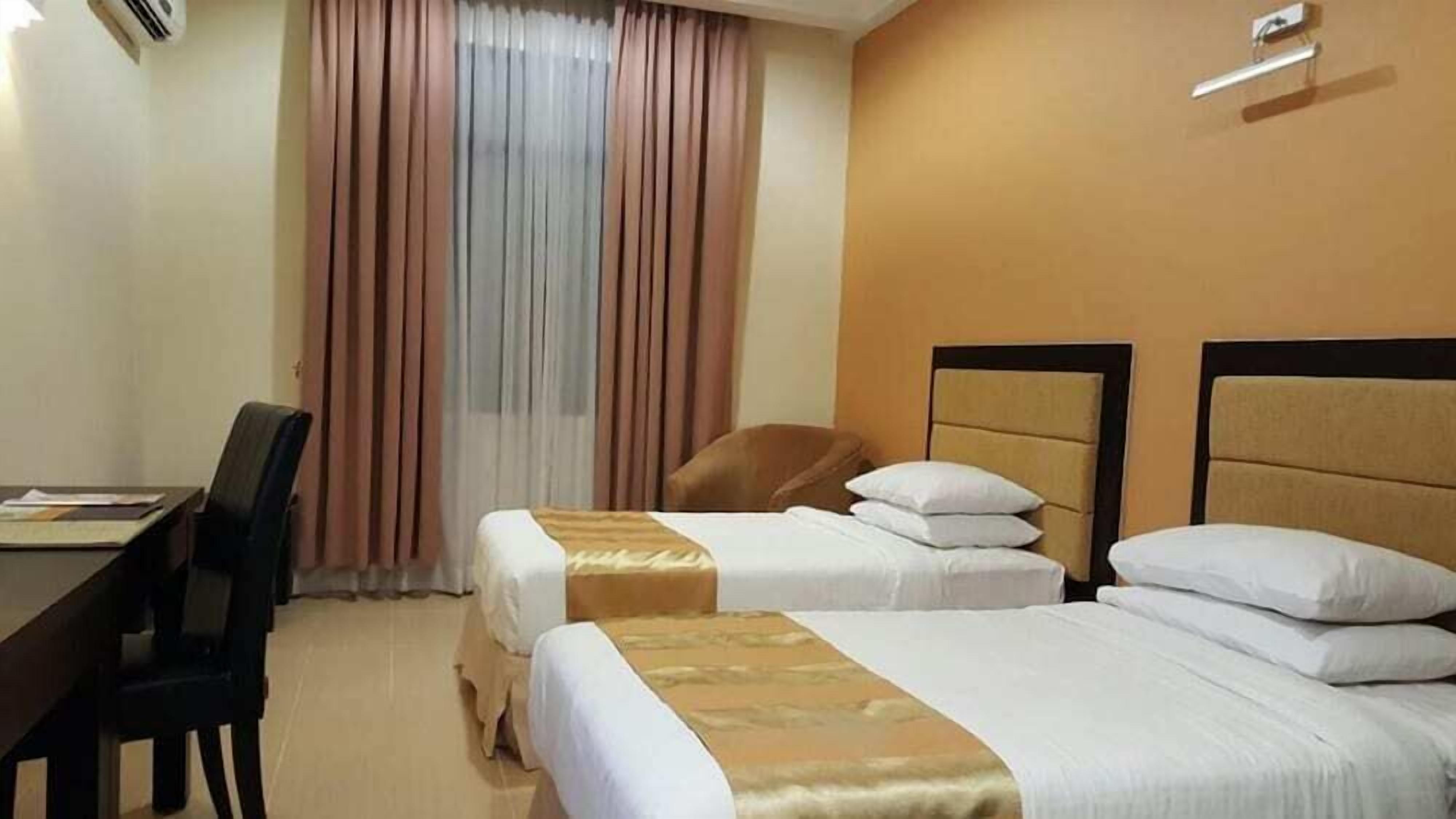 A hotel room with two beds, a desk, and a chair.
