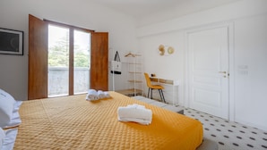 Habitació d'hotel amb un llit, escriptori, cadira i un balcó.