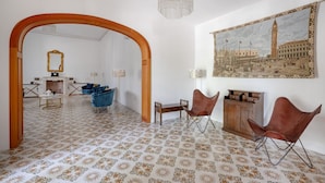 Una habitació amb paviment estampat, un arc de fusta, un quadre d'un paisatge urbà i dues cadires de pell.