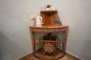 A corner table with a kettle, water bottles, and a shelf with cups and a jug. - Marugarh (Jodhpur)