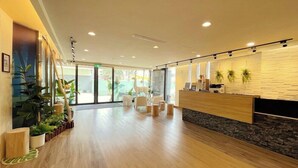 A modern reception area with a wooden reception desk, white chairs, and potted plants. - Fortuna Hotel Hualien (Hualien City)