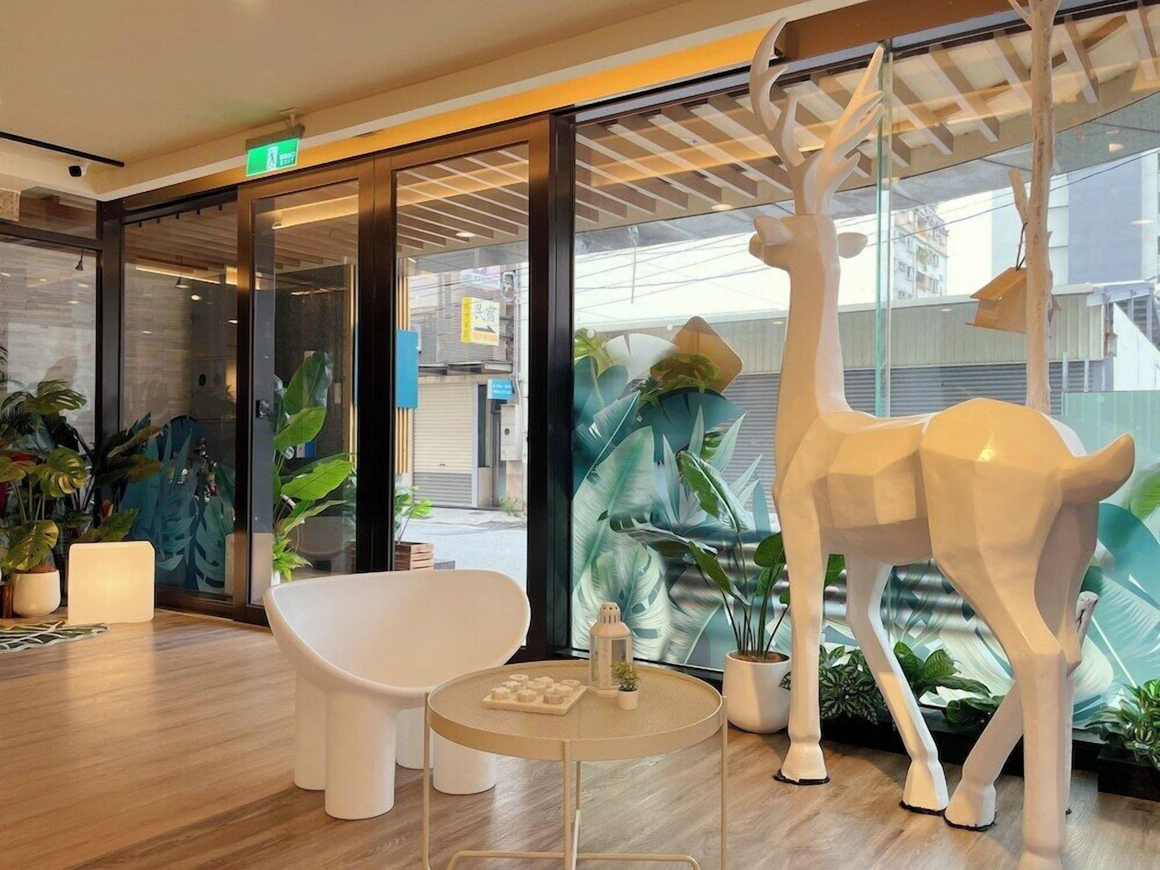 Un intérieur moderne avec un canapé blanc, une table ronde et une sculpture de girafe.