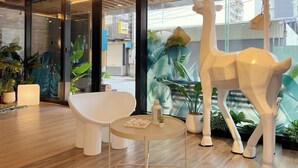 A modern interior with a white sofa, a round table, and a giraffe sculpture. - Fortuna Hotel Hualien (Hualien City)