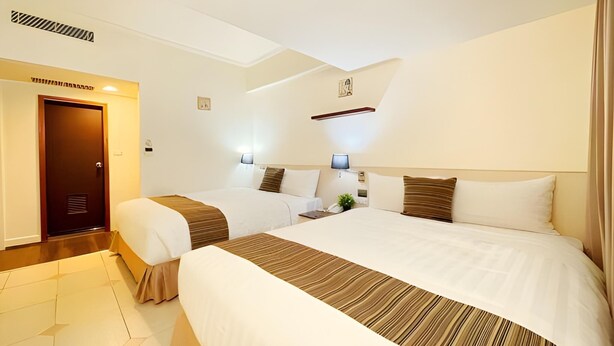 A hotel room with two beds, a wooden floor, a door, and a wall-mounted shelf. - Fortuna Hotel Hualien (Hualien City)