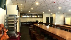 A restaurant with long wooden tables, stools, and a high ceiling with patterned tiles. - Fortuna Hotel Hualien (Hualien City)
