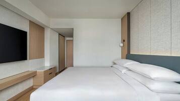 Quarto de hotel moderno com uma cama grande, televisão integrada e um guarda-roupa.