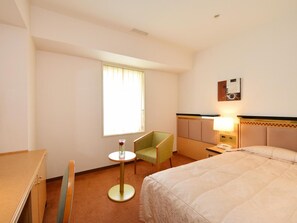 A hotel room with a bed, a desk, a chair, a small table with a vase, and a window with curtains. - Hotel Crown Palais Kobe (Kobe)