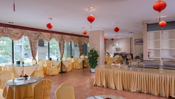A hotel dining area with round tables, chairs, and red lanterns. - Vienna Hotel (Dongguan)