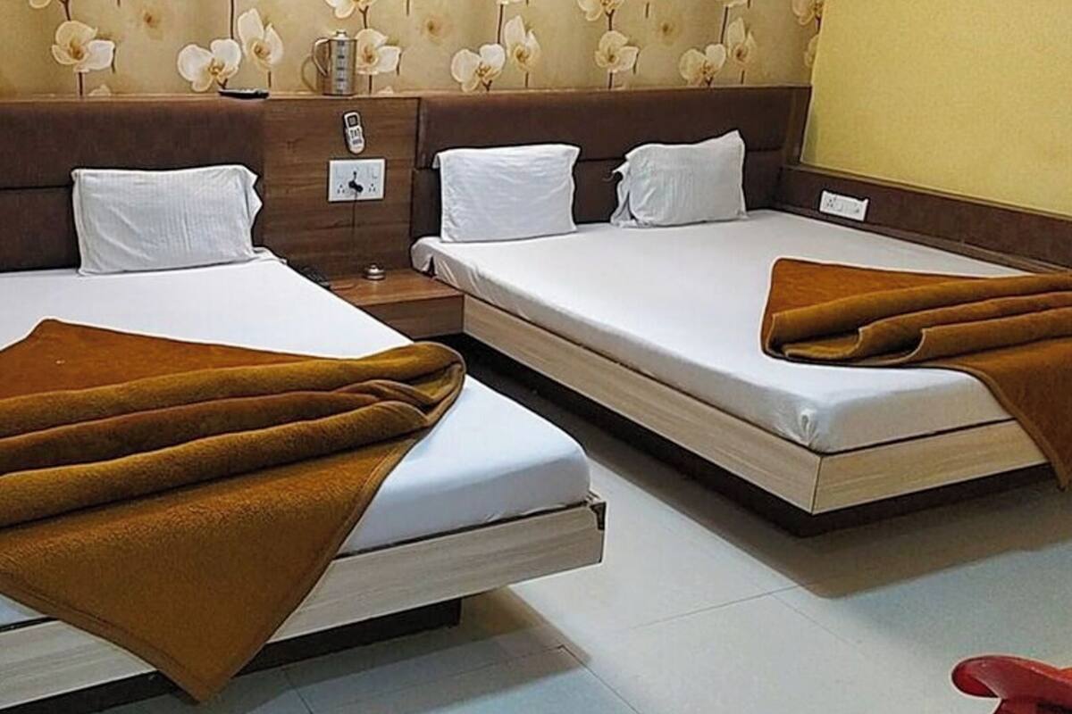 A hotel room with two beds, each with white linens and brown throw blankets.