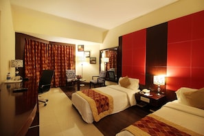 Une chambre d’hôtel avec deux lits, un bureau avec une lampe, une chaise et un grand miroir.