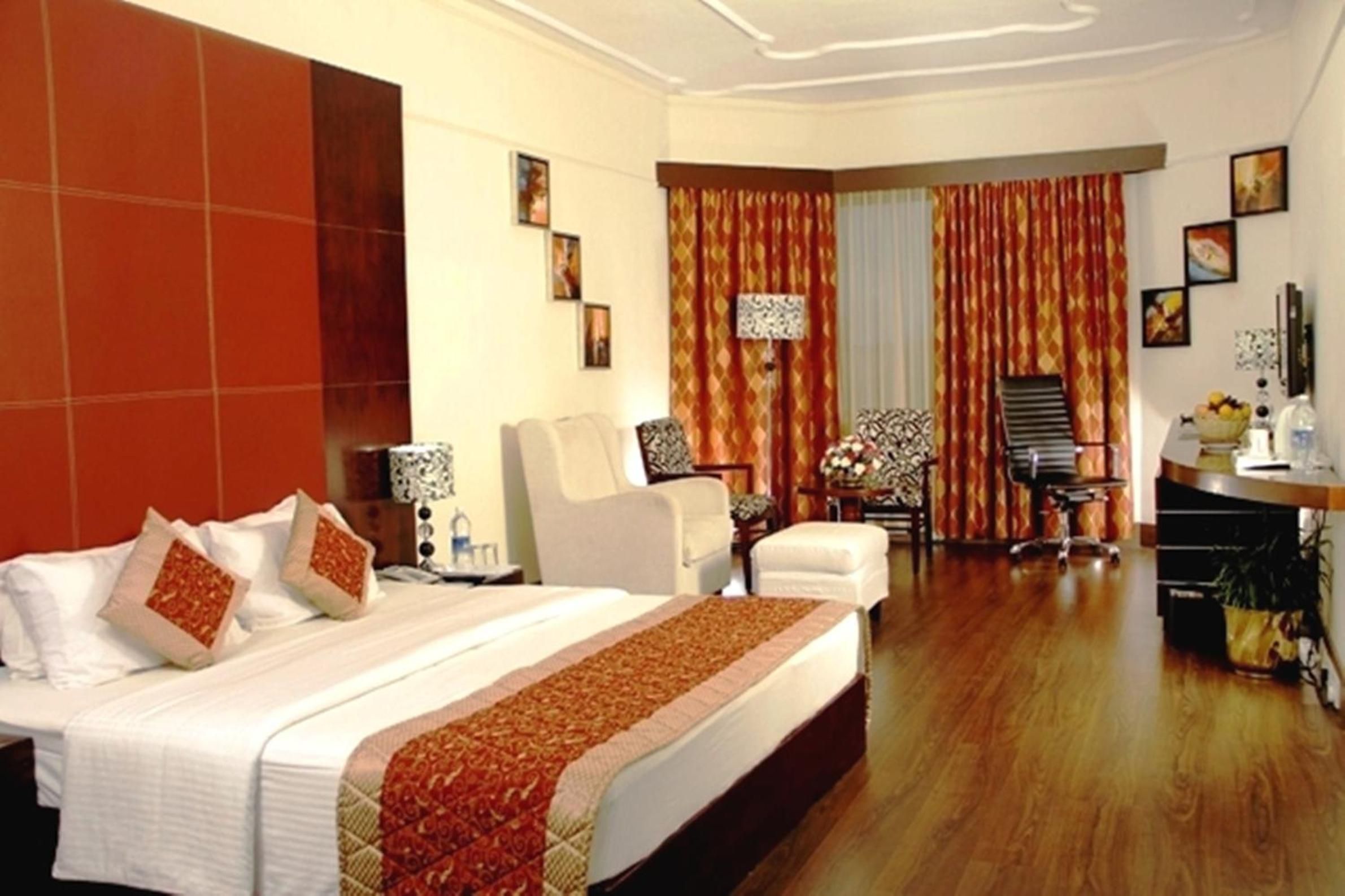 A hotel room with a large bed, two armchairs, a desk, and a chair.