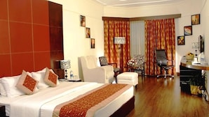 Une chambre d’hôtel avec un grand lit, deux fauteuils, un bureau et une chaise.