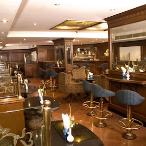 Zona de bar con taburetes altos, mostrador y área de estar con sillas estampadas.