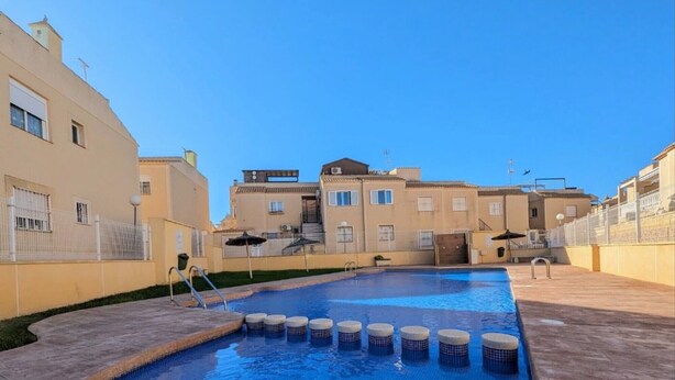 Una piscina con bordo piastrellato, circondata da edifici con balconi e finestre.