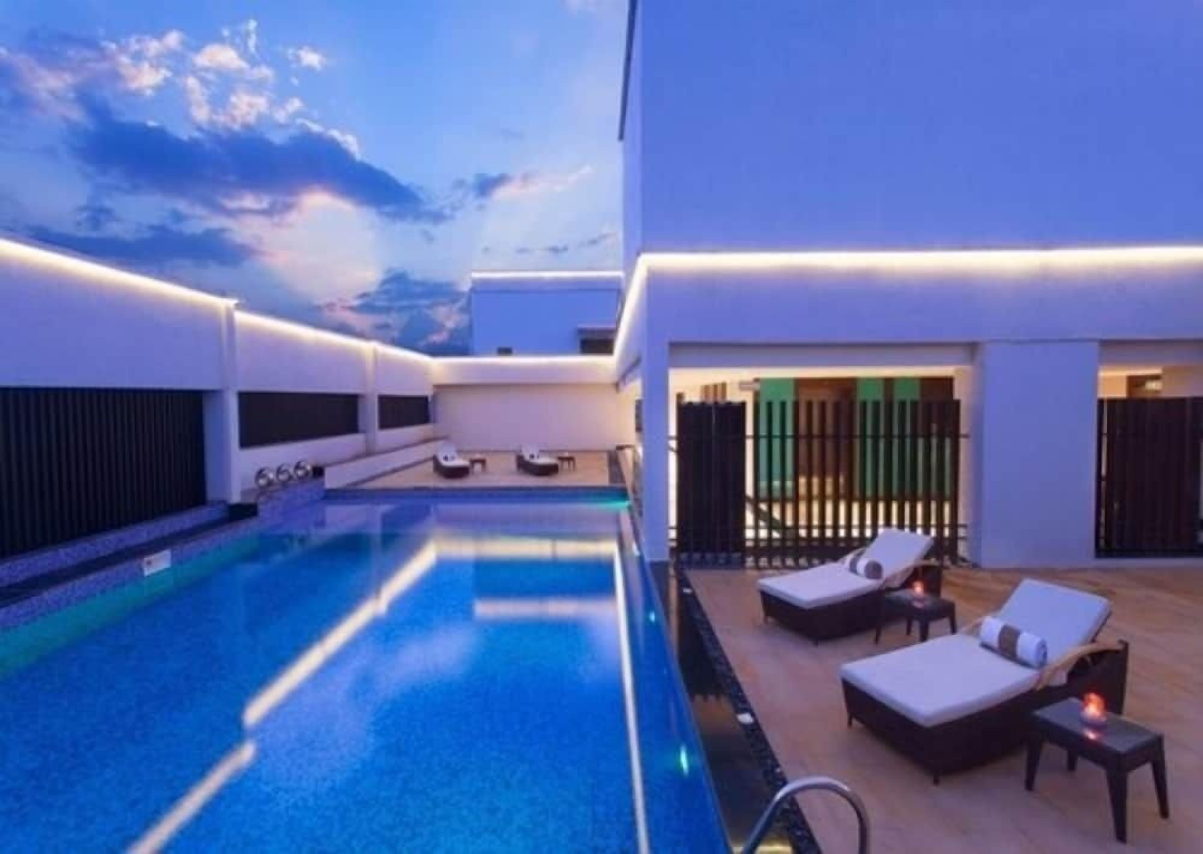 Zona de piscina en la azotea con sillones y vistas al cielo.