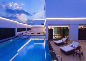 A rooftop pool area with lounge chairs and a view of the sky. - Hycinth Hotels (Thiruvananthapuram)
