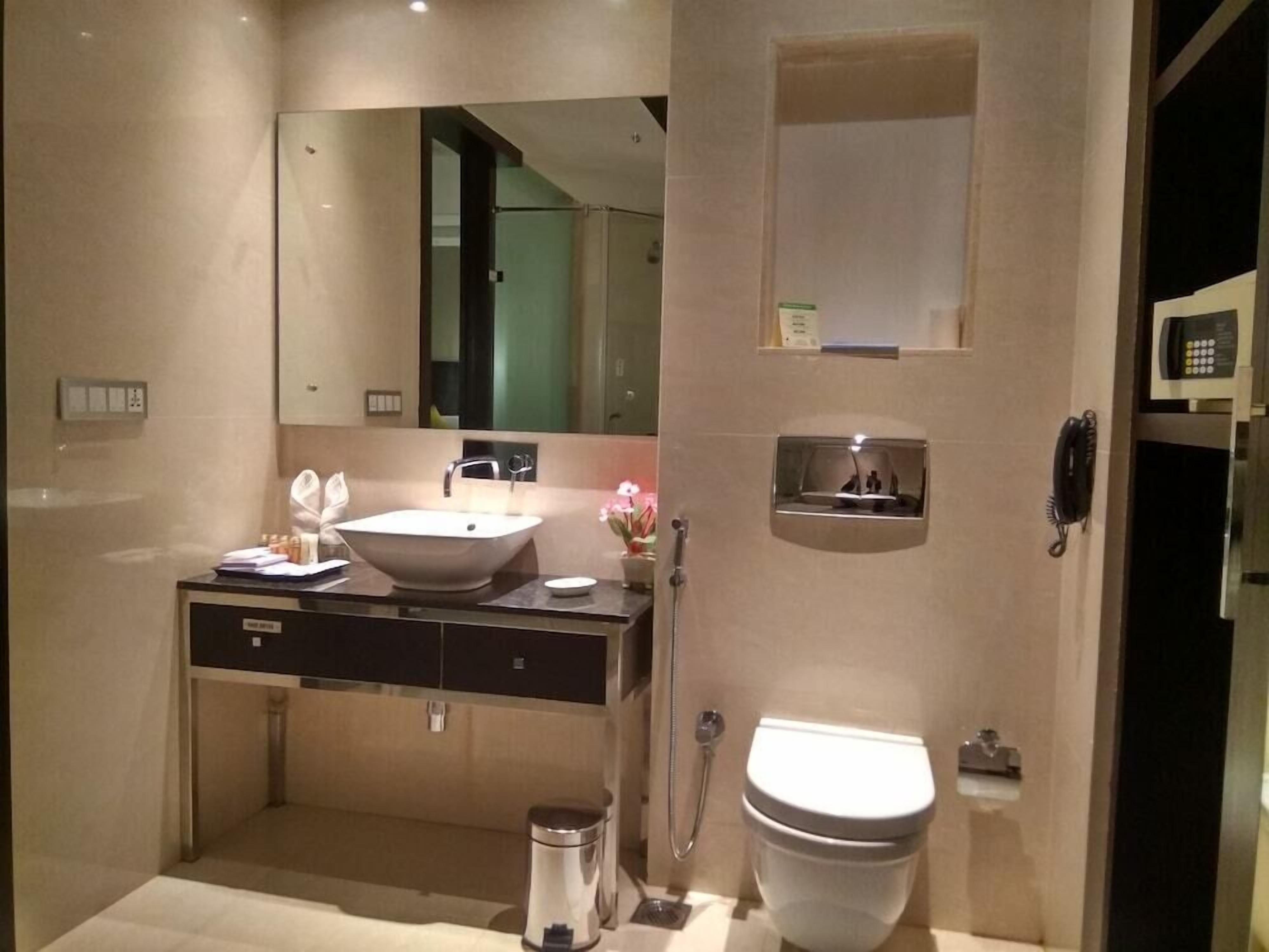 A modern bathroom with a large mirror, a sink, a toilet, and a shower.