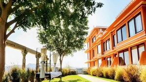 A well-maintained outdoor area with a lawn, a pergola with a table, and a modern building with large windows. - Fateh Garh (Udaipur)