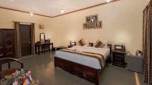 Une chambre d’hôtel avec un grand lit, un bureau, une chaise, une petite table et un ventilateur de plafond.