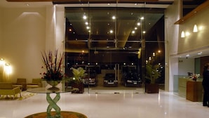 Eine moderne Lobby mit Glastisch, Sitzecke und Blick auf geparkte Autos durch die Glasfenster.