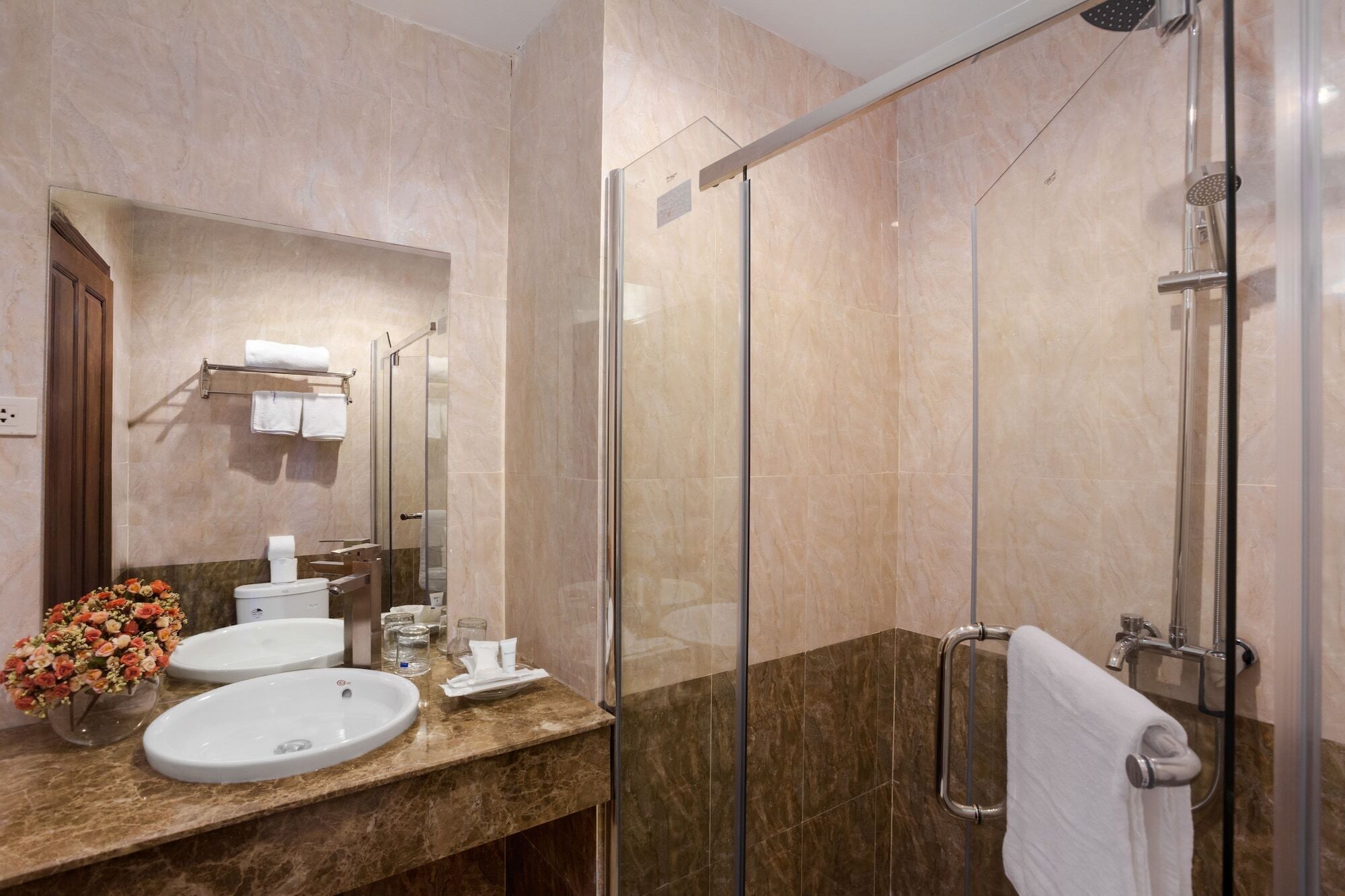 A modern bathroom with two sinks, a glass shower enclosure, and a marble countertop.