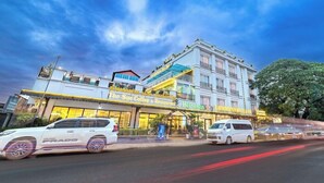 Un hôtel à plusieurs étages, une enseigne bien visible indiquant « The Sun Coffee & Restaurant », et une enseigne « Heineken ».