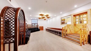 A spacious room with a long wooden bench, a wooden partition with lattice design, and a wooden door with glass panels. - E Square the Fern Pune (Pune)