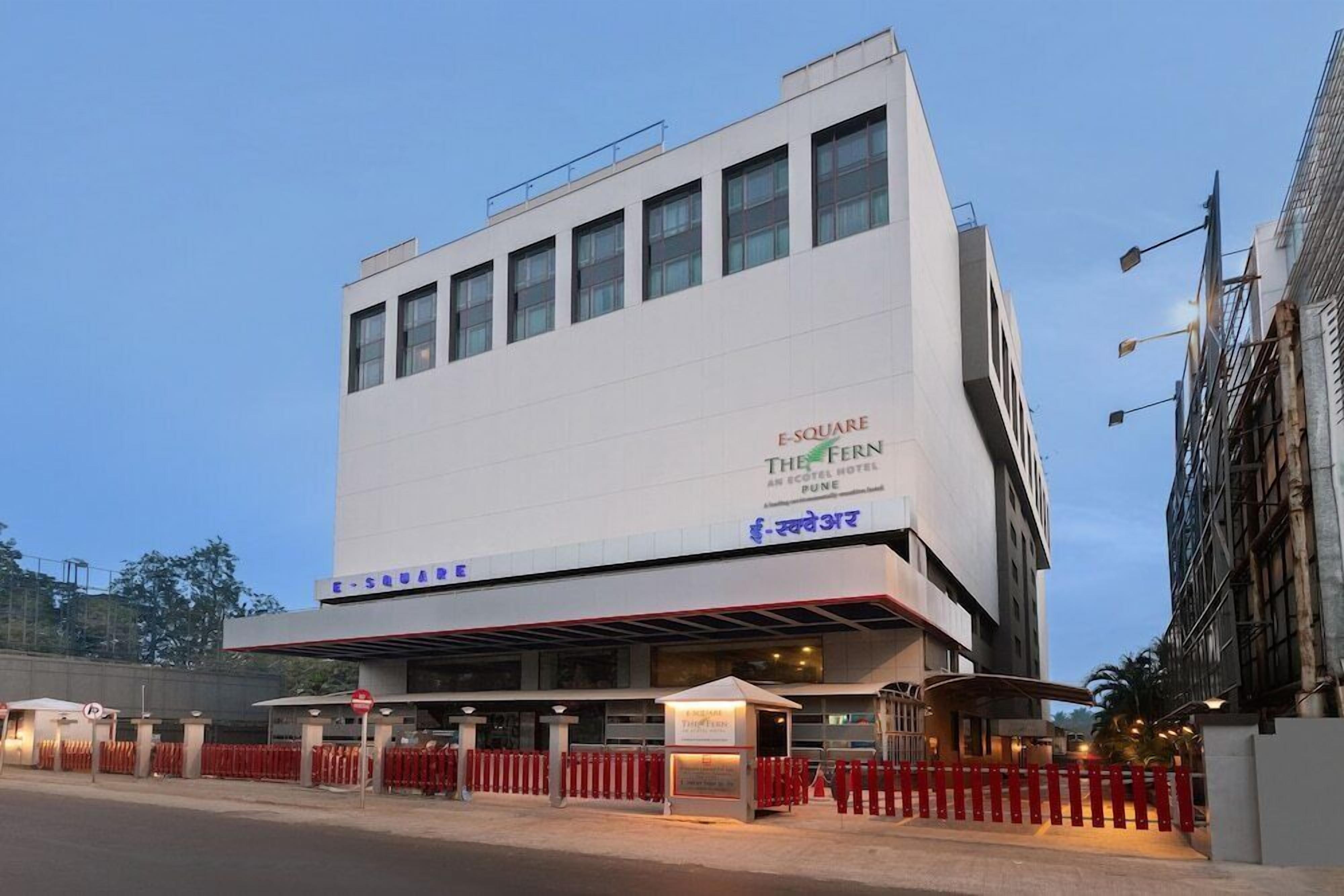 A modern hotel building with a prominent sign for "The Fern E-Square Hotel Pune".