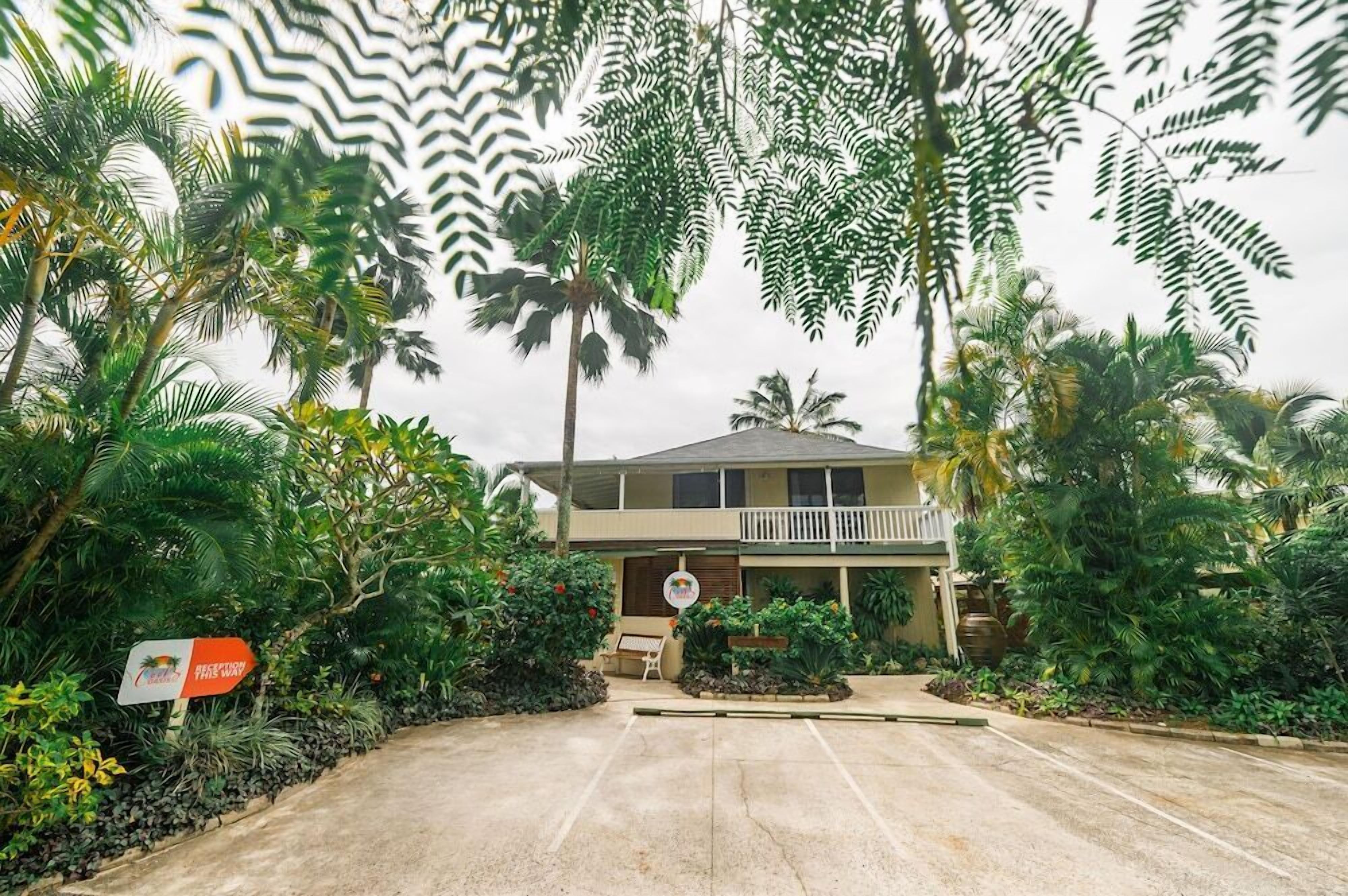 A hotel with a two-story structure, a covered outdoor seating area, and lush tropical vegetation.