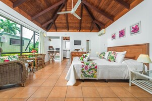 Una habitación amplia con una cama grande, una zona de comedor y vistas al exterior.