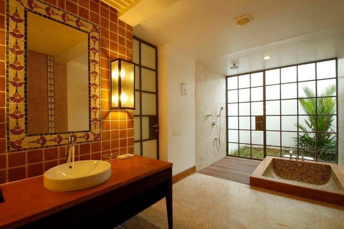 Une salle de bain comprenant un grand miroir, un lavabo, un espace douche et une baignoire.