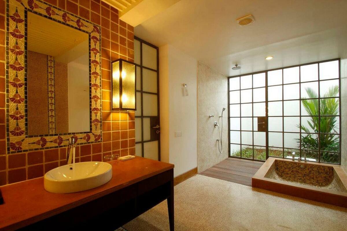 Un baño con un espejo grande, un lavabo, zona de ducha y bañera.
