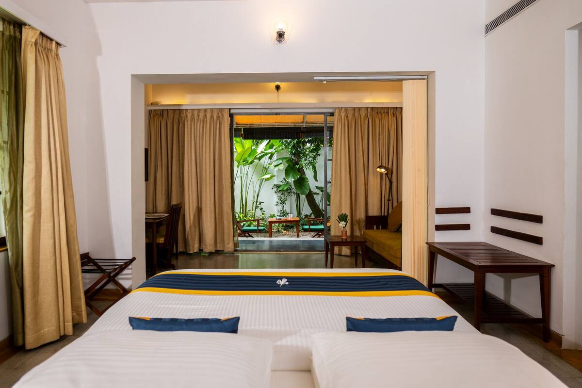 Habitación de hotel con cama, escritorio, silla y vistas a un jardín.