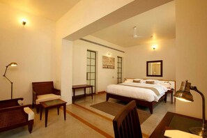 A hotel room with a large bed, a desk, a chair, and a lamp. - Eighth Bastion Fort Kochi - A CGH Earth Experience (Kochi)
