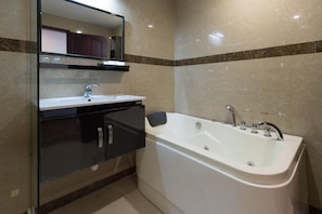 A bathroom with a white bathtub, a vanity with a mirror, and a sink. - No 18 Hotel (Kochi)