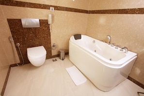 A bathroom with a bathtub, toilet, and a hand dryer.