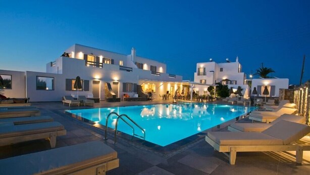 A modern hotel with a swimming pool, lounge chairs, and a well-lit outdoor area. - Anna Maria Mykonos Hotel (Mykonos)